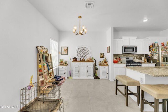 14423 Kayla Mia Dr, El Paso, TX 79938 - kitchen with stainless steel appliances, tasteful backsplash, white cabinetry, a kitchen bar, and a chandelier