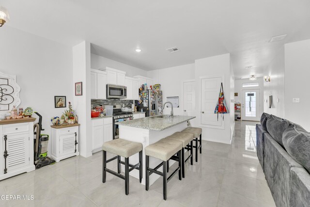14423 Kayla Mia Dr, El Paso, TX 79938 - kitchen featuring stainless steel appliances, a breakfast bar, a sink, open floor plan, and tasteful backsplash