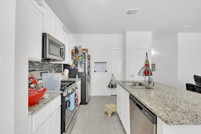 14423 Kayla Mia Dr, El Paso, TX 79938 - kitchen featuring appliances with stainless steel finishes, a sink, light tile patterned floors, white cabinets, and decorative backsplash