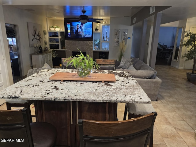 7000 Armistad Ave, El Paso, TX 79912 - kitchen featuring ceiling fan, a fireplace, and light stone counters