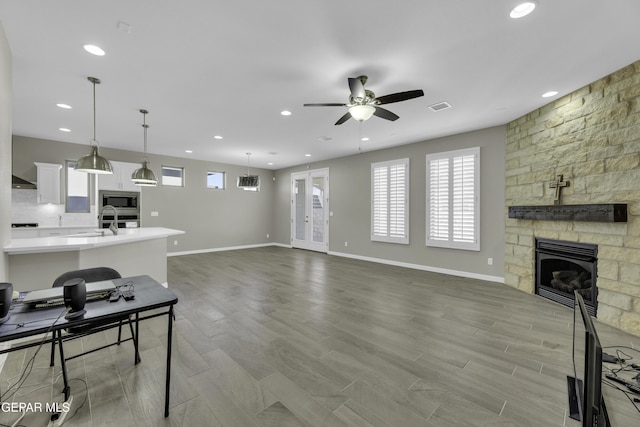 912 Malven Pl, El Paso, TX 79928 - unfurnished living room featuring ceiling fan, a stone fireplace, light wood-type flooring, and recessed lighting