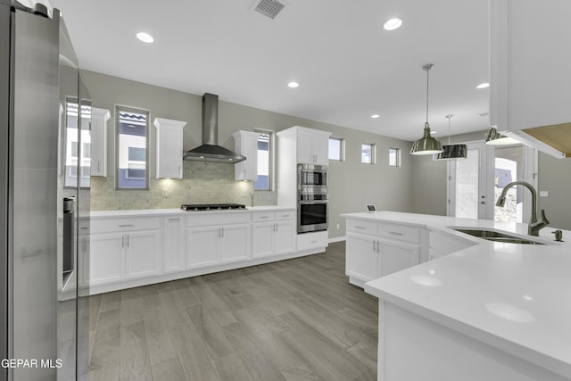 912 Malven Pl, El Paso, TX 79928 - kitchen featuring wall chimney exhaust hood, stainless steel appliances, decorative backsplash, decorative light fixtures, and light countertops