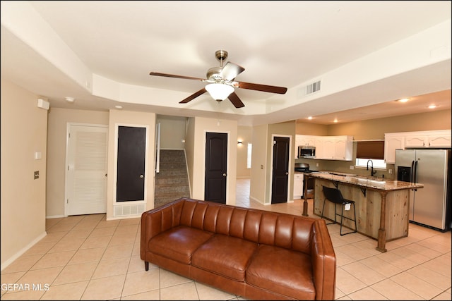 12712 Tierra Aurora Dr, El Paso, TX 79938 - living area featuring light tile patterned floors, ceiling fan, stairway, and a tray ceiling