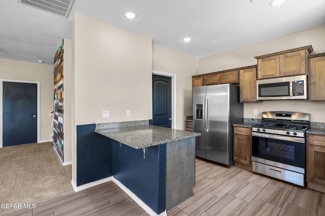 11470 Dawn View Rd Unit B, Socorro, TX 79927 - kitchen with appliances with stainless steel finishes, wood finish floors, dark stone countertops, a kitchen bar, and recessed lighting