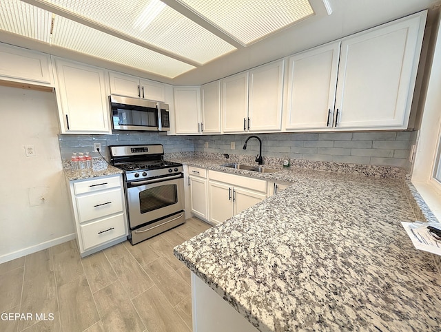 3425 Dialrock Ln, El Paso, TX 79935 - kitchen with stainless steel appliances, light stone counters, white cabinetry, and decorative backsplash