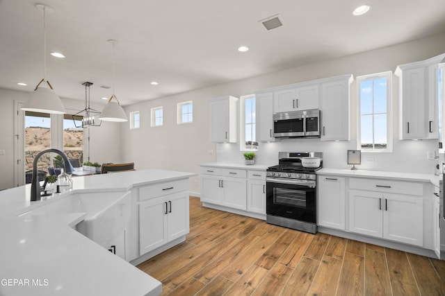 905 Bilton Pl, El Paso, TX 79928 - kitchen featuring appliances with stainless steel finishes, light countertops, light wood-type flooring, white cabinets, and backsplash
