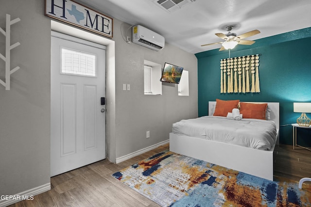 3031 Memphis Ave, El Paso, TX 79930 - bedroom featuring a wall unit AC, wood finished floors, and a ceiling fan