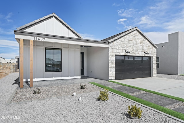 3932 Surmise St, El Paso, TX 79938 - view of front of house with board and batten siding, stone siding, an attached garage, and concrete driveway