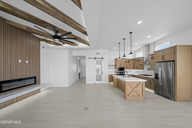 3932 Surmise St, El Paso, TX 79938 - kitchen with appliances with stainless steel finishes, a barn door, open floor plan, light countertops, and wall chimney exhaust hood