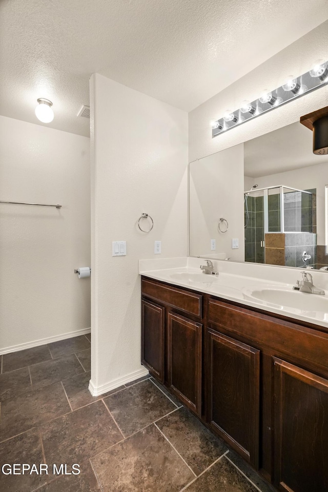 5036 Silver Ranch Ave, El Paso, TX 79934 - full bathroom with double vanity, a stall shower, a textured ceiling, and stone finish floors