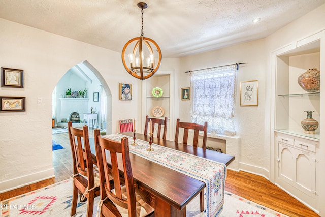 4021 Hastings Dr, El Paso, TX 79903 - dining area featuring arched walkways, light wood-type flooring, a chandelier, built in features, and a textured ceiling