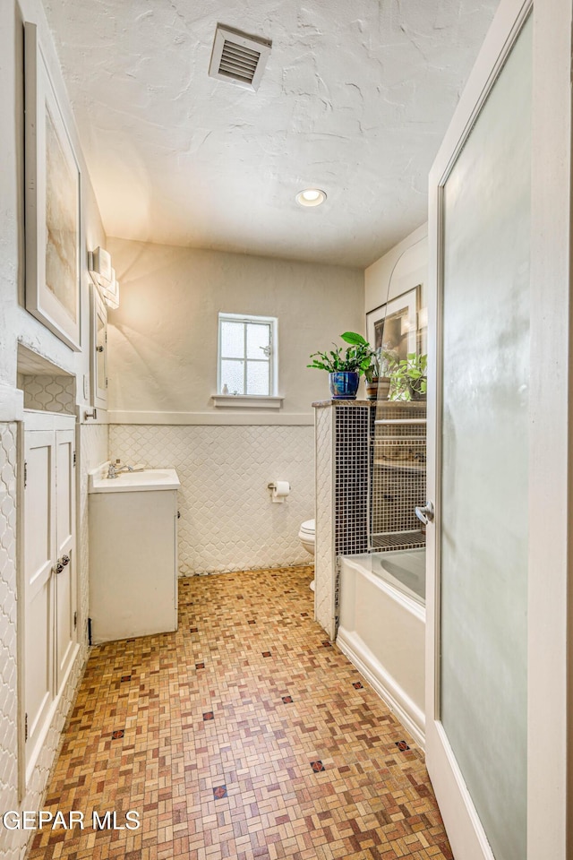 4021 Hastings Dr, El Paso, TX 79903 - bathroom featuring tile walls, a bath, vanity, wainscoting, and recessed lighting