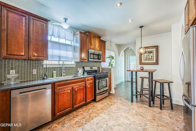 4021 Hastings Dr, El Paso, TX 79903 - kitchen with appliances with stainless steel finishes, dark countertops, backsplash, arched walkways, and hanging light fixtures