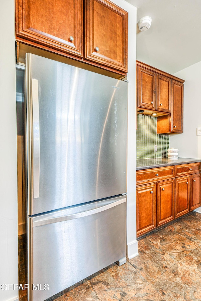 4021 Hastings Dr, El Paso, TX 79903 - kitchen with freestanding refrigerator, tasteful backsplash, brown cabinetry, and stone finish floors