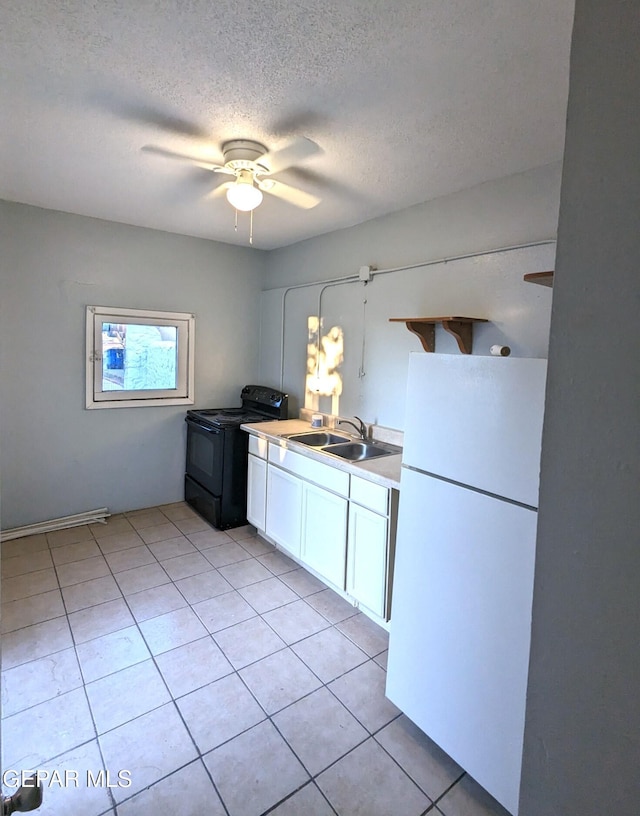 3308 Tularosa Ave, El Paso, TX 79903 - kitchen with freestanding refrigerator, black / electric stove, white cabinets, light tile patterned floors, and a textured ceiling