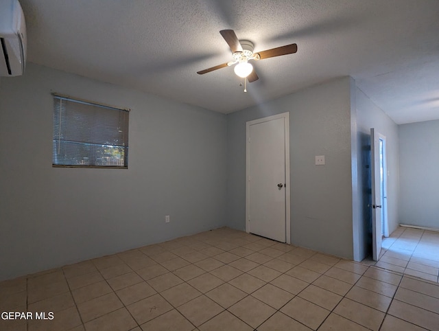 3308 Tularosa Ave, El Paso, TX 79903 - empty room with a wall unit AC, ceiling fan, light tile patterned floors, and a textured ceiling