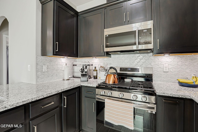 12820 Monmouth Ave, El Paso, TX 79928 - kitchen with appliances with stainless steel finishes, light stone counters, arched walkways, and decorative backsplash
