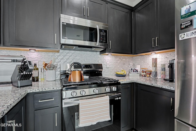 12820 Monmouth Ave, El Paso, TX 79928 - kitchen with appliances with stainless steel finishes, dark cabinets, light stone countertops, and tasteful backsplash