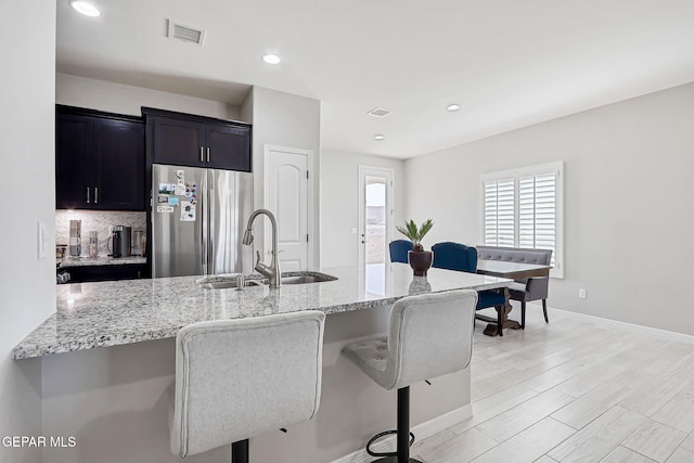 12820 Monmouth Ave, El Paso, TX 79928 - kitchen featuring freestanding refrigerator, light stone countertops, a breakfast bar, tasteful backsplash, and recessed lighting