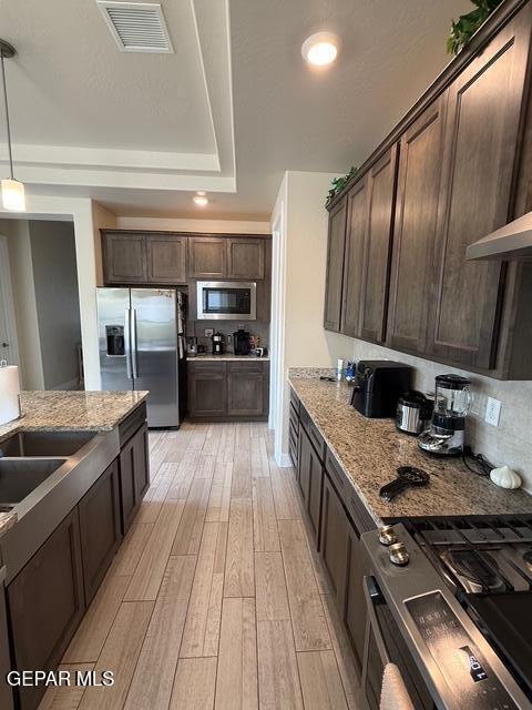2313 Dancing Piper Way, El Paso, TX 79911 - kitchen featuring appliances with stainless steel finishes, dark brown cabinetry, light wood-style floors, light stone counters, and recessed lighting