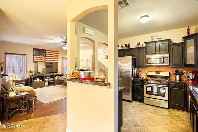 5004 Gold Ranch Ave, El Paso, TX 79934 - kitchen with stainless steel appliances, arched walkways, dark countertops, ceiling fan, and light tile patterned floors