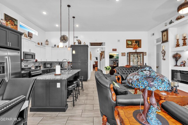 12328 Desert Heights Ct, El Paso, TX 79938 - kitchen featuring appliances with stainless steel finishes, open floor plan, a breakfast bar area, light stone counters, and backsplash