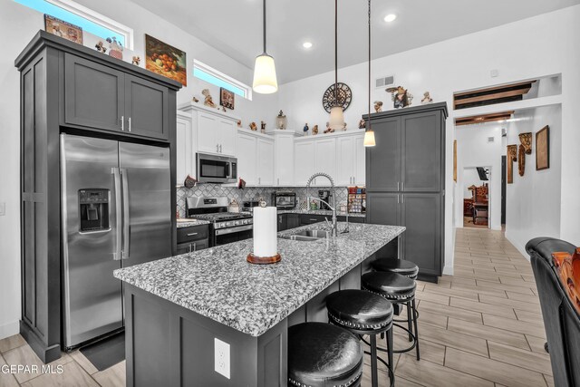 12328 Desert Heights Ct, El Paso, TX 79938 - kitchen with stainless steel appliances, backsplash, light stone countertops, a kitchen bar, and decorative light fixtures