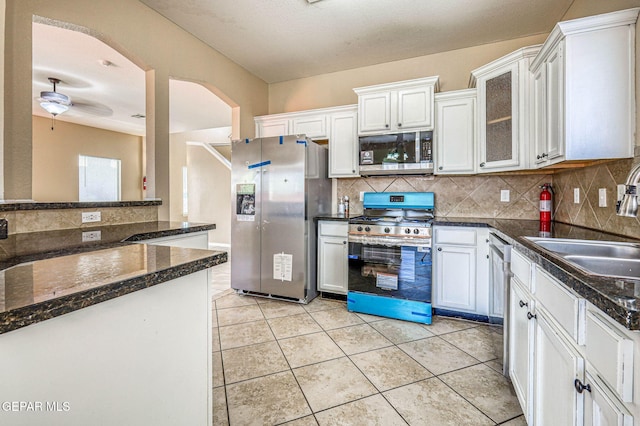14376 N Cave Dr, El Paso, TX 79938 - kitchen with stainless steel appliances, decorative backsplash, arched walkways, white cabinetry, and light tile patterned floors