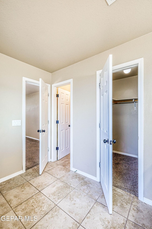 14376 N Cave Dr, El Paso, TX 79938 - unfurnished bedroom featuring light tile patterned floors, a walk in closet, a closet, and light colored carpet