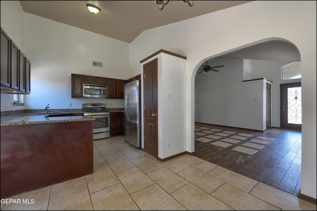 4908 Gold Ranch Ave, El Paso, TX 79934 - kitchen featuring appliances with stainless steel finishes, arched walkways, a ceiling fan, light tile patterned flooring, and dark brown cabinets