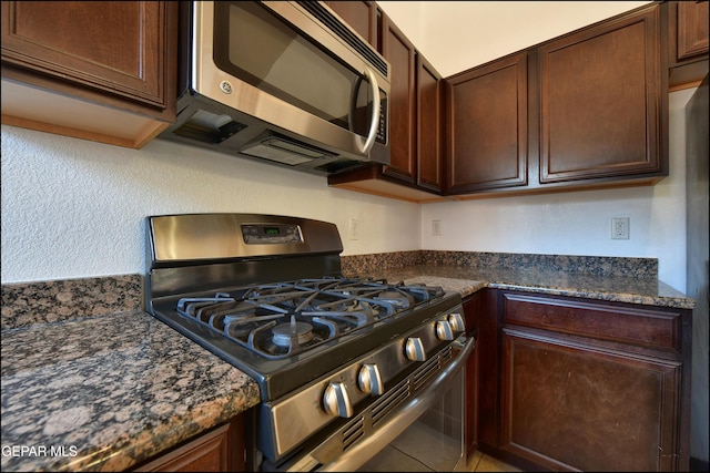 4908 Gold Ranch Ave, El Paso, TX 79934 - kitchen with appliances with stainless steel finishes, dark brown cabinets, and dark stone countertops