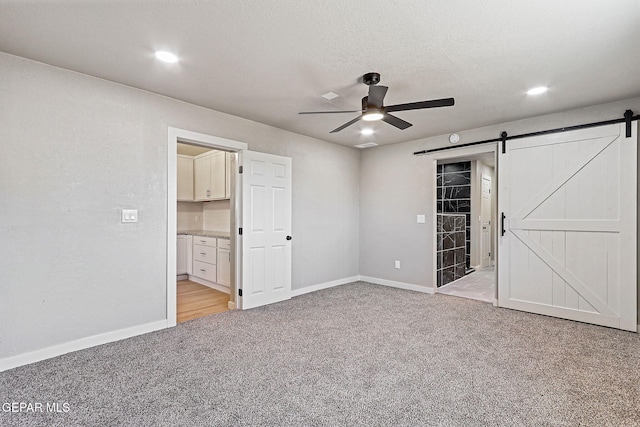 5112 Sun Valley Dr, El Paso, TX 79924 - unfurnished bedroom with a barn door, light carpet, recessed lighting, ceiling fan, and ensuite bath