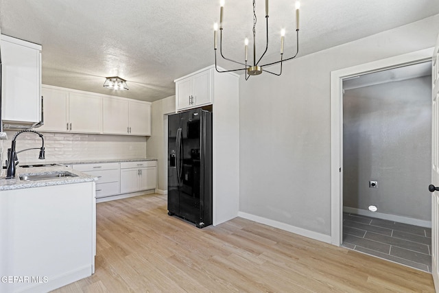 5112 Sun Valley Dr, El Paso, TX 79924 - kitchen with black fridge, a chandelier, white cabinetry, light wood finished floors, and a textured ceiling