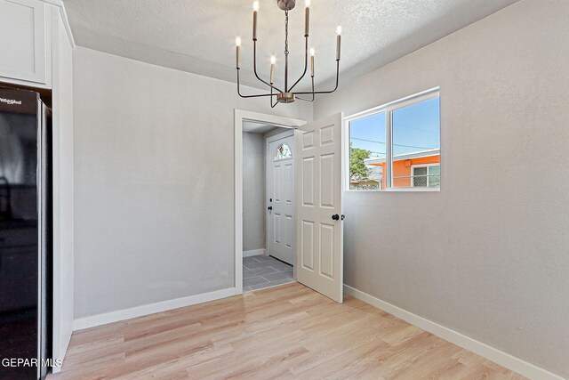 5112 Sun Valley Dr, El Paso, TX 79924 - unfurnished dining area with a chandelier, light wood finished floors, and a textured ceiling