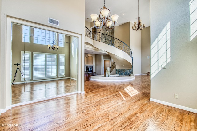 6570 Eagle Ridge Dr, El Paso, TX 79912 - foyer featuring a chandelier, a towering ceiling, a fireplace with raised hearth, wood finished floors, and a textured wall