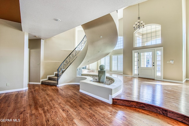 6570 Eagle Ridge Dr, El Paso, TX 79912 - foyer entrance with wood finished floors, a chandelier, stairs, a high ceiling, and a textured ceiling