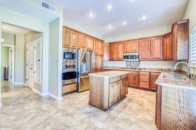 6570 Eagle Ridge Dr, El Paso, TX 79912 - kitchen featuring stainless steel appliances, recessed lighting, a kitchen island, brown cabinets, and a textured ceiling