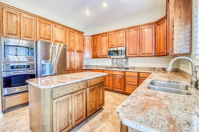 6570 Eagle Ridge Dr, El Paso, TX 79912 - kitchen with appliances with stainless steel finishes, a center island, brown cabinets, recessed lighting, and light stone countertops