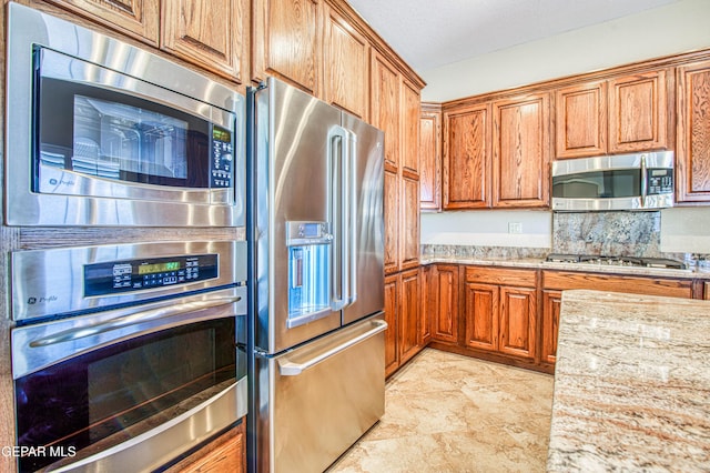6570 Eagle Ridge Dr, El Paso, TX 79912 - kitchen with appliances with stainless steel finishes, brown cabinets, and light stone counters