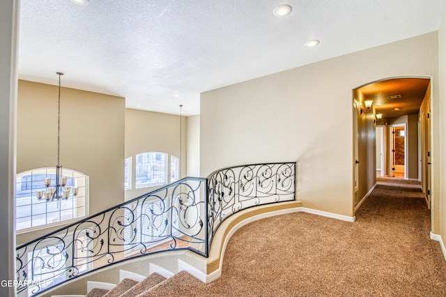6570 Eagle Ridge Dr, El Paso, TX 79912 - corridor with a chandelier, carpet floors, a textured ceiling, arched walkways, and recessed lighting