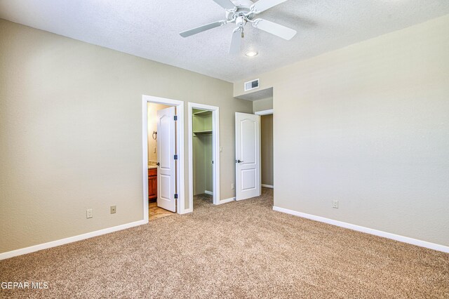 6570 Eagle Ridge Dr, El Paso, TX 79912 - unfurnished bedroom featuring light carpet, a walk in closet, a closet, a textured ceiling, and ceiling fan