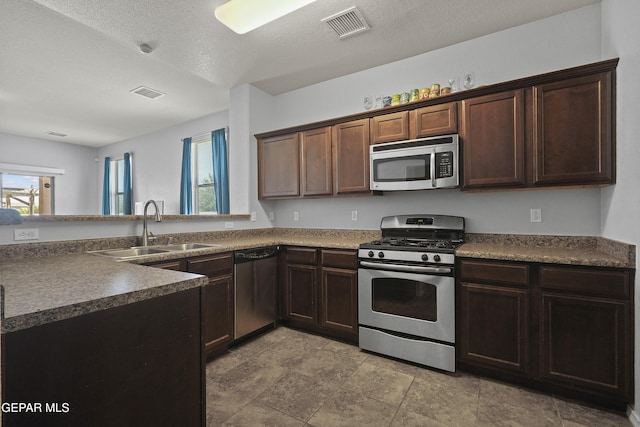 14477 Jacinto Ramos Ave, El Paso, TX 79938 - kitchen featuring stainless steel appliances, healthy amount of natural light, dark countertops, dark brown cabinetry, and a textured ceiling