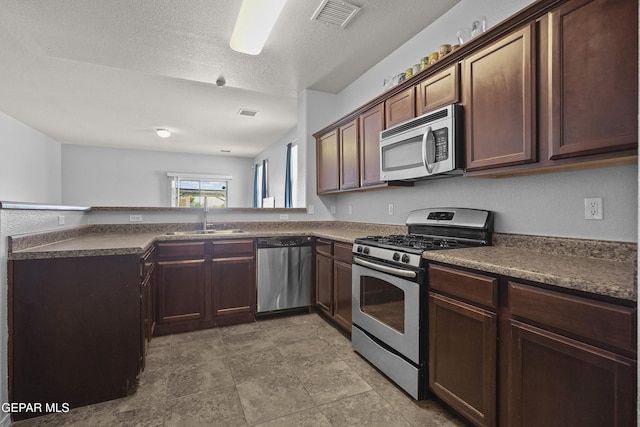 14477 Jacinto Ramos Ave, El Paso, TX 79938 - kitchen featuring stainless steel appliances, dark countertops, a textured ceiling, and a peninsula
