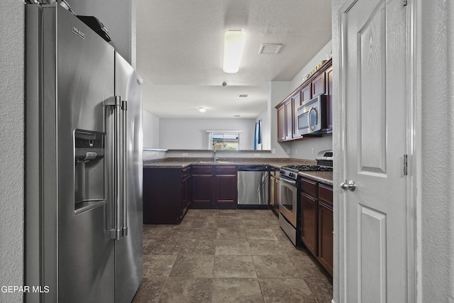 14477 Jacinto Ramos Ave, El Paso, TX 79938 - kitchen with appliances with stainless steel finishes, dark countertops, stone finish floors, and a textured ceiling