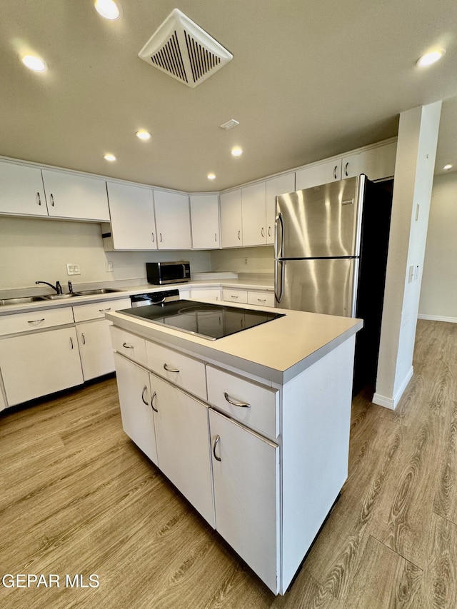 536 Satellite Dr, El Paso, TX 79912 - kitchen with light wood-style flooring, appliances with stainless steel finishes, a center island, recessed lighting, and white cabinetry