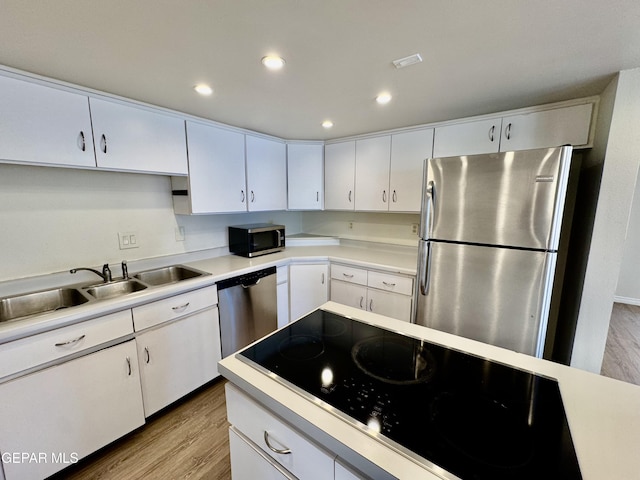 536 Satellite Dr, El Paso, TX 79912 - kitchen featuring appliances with stainless steel finishes, wood finished floors, light countertops, white cabinetry, and recessed lighting