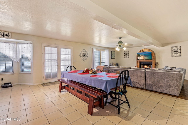 9769 Galilee Dr, El Paso, TX 79927 - dining area with light tile patterned flooring, a ceiling fan, a lit fireplace, and a textured ceiling