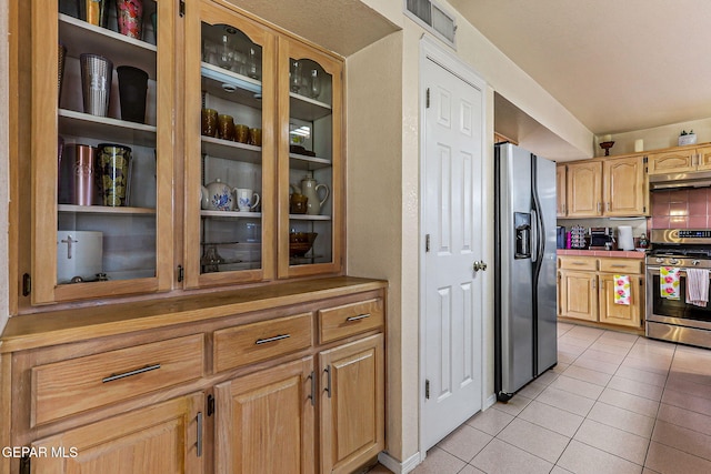 9769 Galilee Dr, El Paso, TX 79927 - kitchen featuring appliances with stainless steel finishes, under cabinet range hood, light tile patterned flooring, and glass insert cabinets