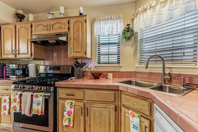 9769 Galilee Dr, El Paso, TX 79927 - kitchen with under cabinet range hood, stainless steel range with gas stovetop, white dishwasher, tile countertops, and decorative backsplash