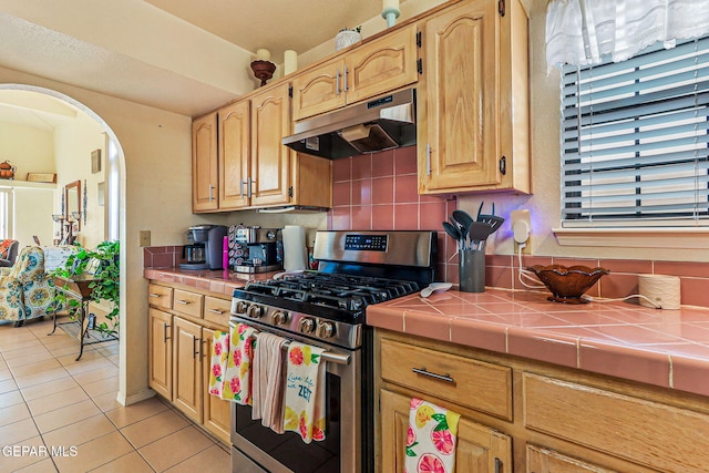9769 Galilee Dr, El Paso, TX 79927 - kitchen featuring stainless steel gas range, under cabinet range hood, tile counters, and light tile patterned floors